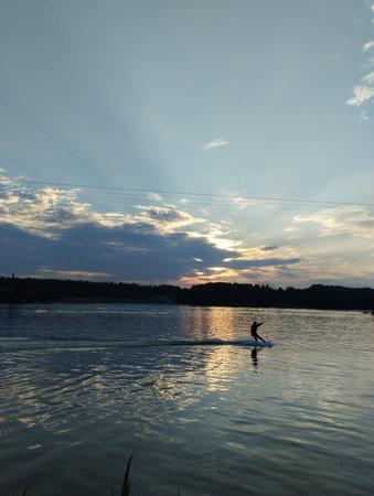 Silhouette of a man on a paddle board at sunset in the summerの写真素材