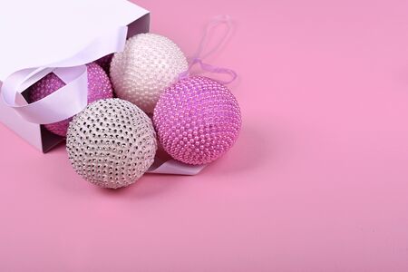 pink Christmas balls from a white package on a pink backgroundの写真素材