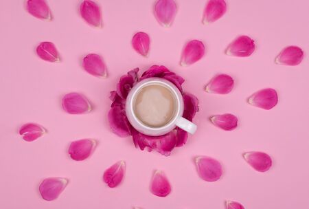 Cup of coffee in the dynamics of rose petals on a pink background, top viewの写真素材