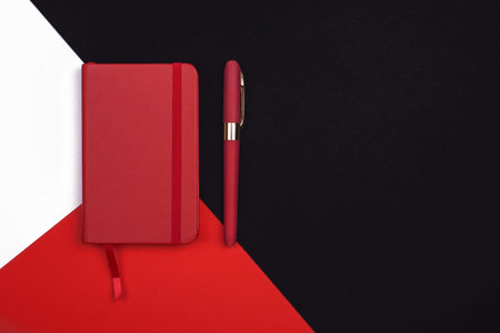red Notepad with pen on red, white and black background. Top view. flat lay