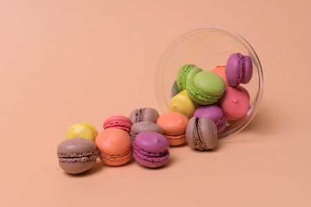 Colorful mini macarons a scattering of packaging on orange background, sweetの写真素材