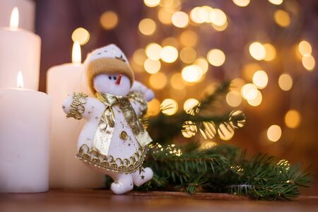 Christmas tree branches, with a snowman and a candle. Bokeh in the background. Christmas card. New Year 2020の写真素材