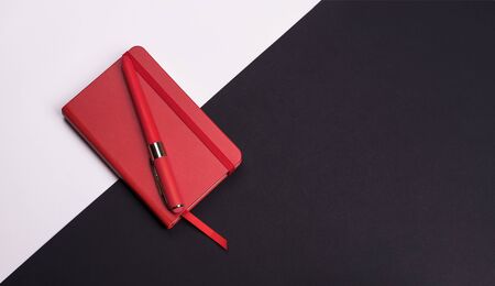 red Notepad with pen on white and black background. Top view. flat layの写真素材