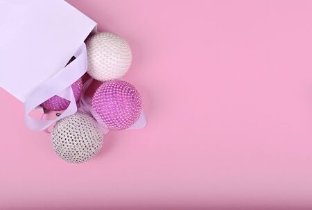 pink and white Christmas balls from a white package on pink backgroundの写真素材