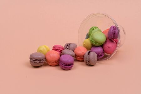 Colorful mini macarons a scattering of packaging on orange background, sweetの写真素材