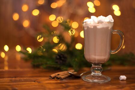 Cacao drink in a glass with marshmallow on the background of bokeh lights, hot Christmas drinkの写真素材