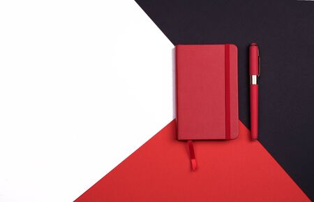red Notepad with pen on red, white and black background. Top view. flat layの写真素材