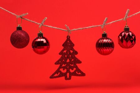 New Year Christmas background. Red Christmas toys balls on a string with clothespins on a red background, preparing for the new year and Christmas.の写真素材