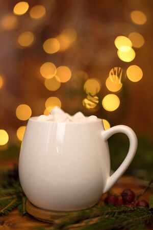 sweet cocoa in a white cup with marshmallow on the background of bokeh lights, Christmas drink. Christmas decoration and bokeh of light in backgroundの写真素材