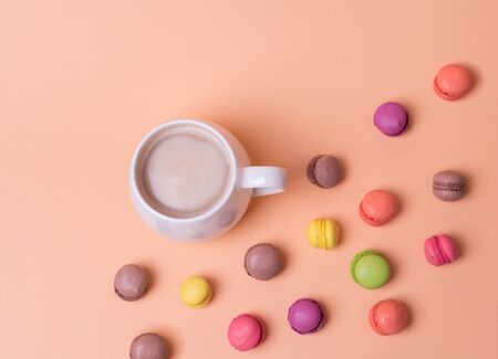 White Cup of fragrant cappuccino with macarons cakes on orange background, top viewの写真素材