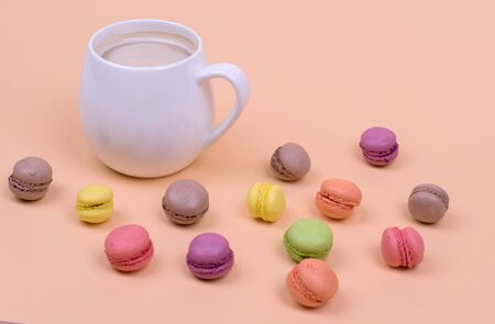 White Cup of fragrant cappuccino with macaroni cakes on orange background, top viewの写真素材