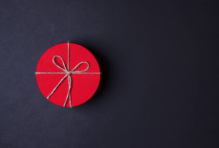 Closed red round gift box on black background. the view from the top. Gift for the holidays of New Year, Christmas, Valentine's day, March 8.の写真素材