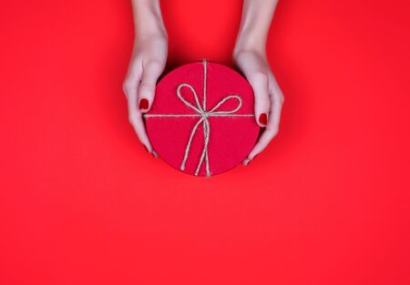 Closed red round gift box on red background. the view from the top. Gift for the holidays of New Year, Christmas, Valentine's day, March 8.の写真素材