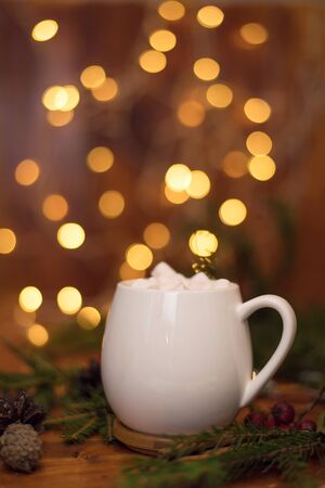 sweet cocoa in a white cup with marshmallow on the background of bokeh lights, Christmas drink. Christmas decoration and bokeh of light in backgroundの写真素材