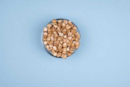 Caramel sweet popcorn glass bowl isolated on blue background top view. Top view, copy space.の写真素材