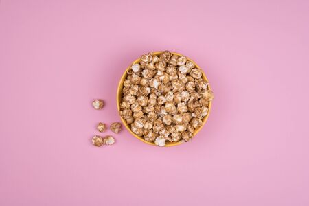 Caramel sweet popcorn bowl isolated on pink background top view. Frame composition with copy space.の写真素材