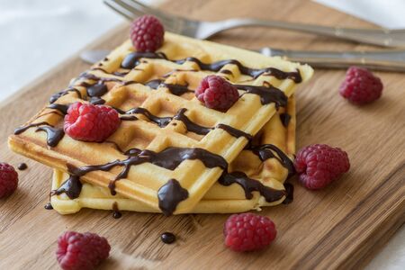 Two Viennese waffles with chocolate and berries on a wooden Boardの写真素材