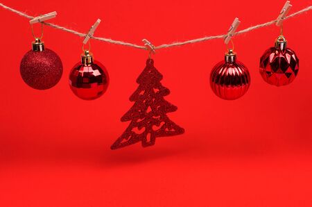 Red Christmas toys balls on a string with clothespins on a red background, preparing for the new year and Christmasの写真素材
