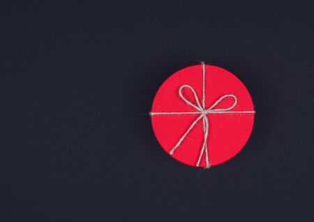 Closed red round gift box on black background. Top view. Gift for the holidays of New Year, Christmas, Valentines day, birthdayの写真素材