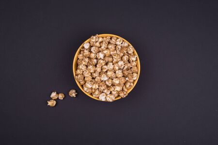 Caramel sweet popcorn bowl isolated on black background top view. Top view, copy space, flat layの写真素材