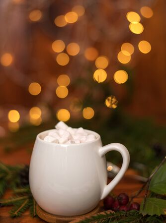 sweet cocoa in a white cup with marshmallow on the background of bokeh lights, Christmas drink. Christmas decoration and bokeh of light in backgroundの写真素材