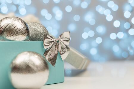 Blue box with silver Christmas balls on the background of blue bokeh lights on white backgroundの写真素材