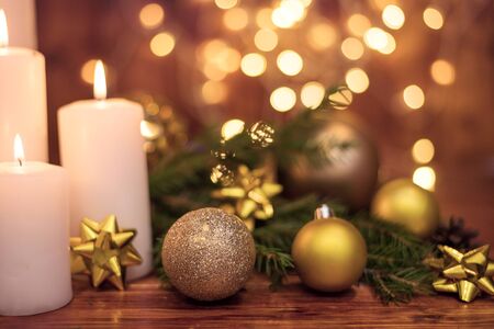 Golden Christmas ball on a tree branch, white candle flame, bokeh lights on a backgroundの写真素材
