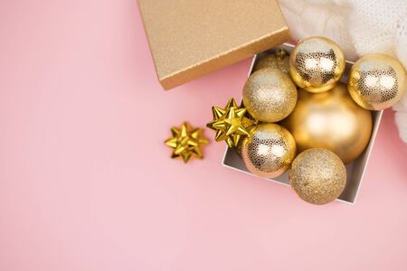 Gold gift box with gold Christmas balls and stars on pink background, mock up, copy space, flat layの写真素材