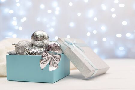Blue box with silver Christmas balls on the background of blue bokeh lights on white backgroundの写真素材
