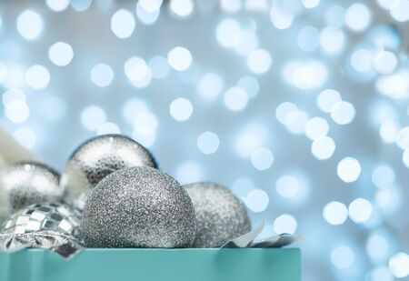Blue box with silver Christmas balls on the background of blue bokeh lights on white backgroundの写真素材