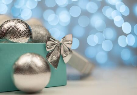 Blue box with silver Christmas balls on the background of blue bokeh lights on white background, New Year and Christmas decorationの写真素材