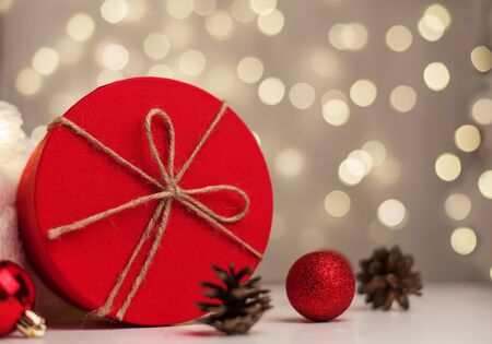 Red Christmas gift box on the background of golden bokeh with Christmas balls and cones, background, postcard.の写真素材