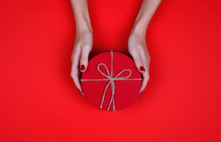 Closed red round gift box on red background. the view from the top. Gift for the holidays of New Year, Christmas, Valentine's day, March 8.の写真素材
