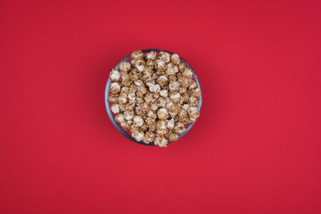 Caramel sweet popcorn bowl isolated on red background top view. Frame composition with copy space.の写真素材