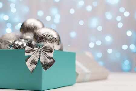 Blue box with silver Christmas balls on the background of blue bokeh lights on white background, New Year and Christmas decorationの写真素材