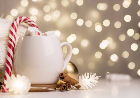cup of hot cocoa with marshmallows and candy canes background with beautiful Christmas lights of bokeh. Coffee. Blurred background.の写真素材