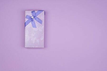 Rectangular purple gift box with bow on purple background,の写真素材