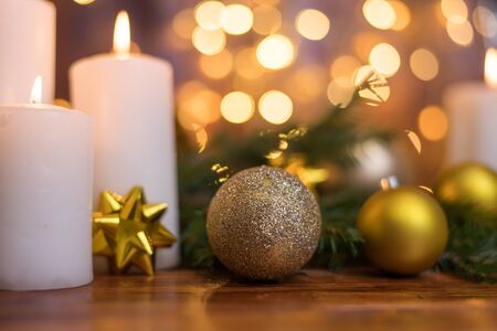 Golden Christmas ball on a tree branch, white candle flame, bokeh lights on a backgroundの写真素材