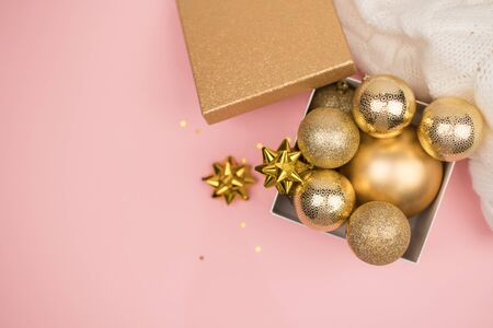 Gold gift box with gold Christmas balls and stars on pink background, mock up, copy space, flat layの写真素材