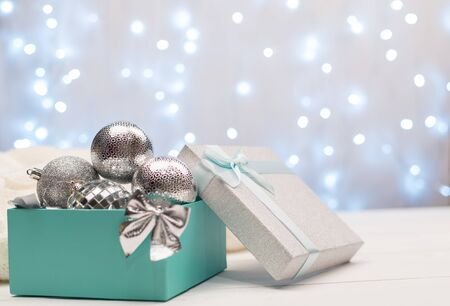Blue box with silver Christmas balls on the background of blue bokeh lights on white backgroundの写真素材