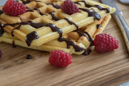 Viennese waffles with chocolate and berries on a wooden Boardの写真素材
