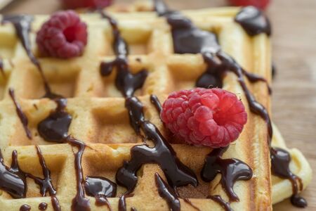 Two Viennese waffles with chocolate and berries on a wooden Boardの写真素材