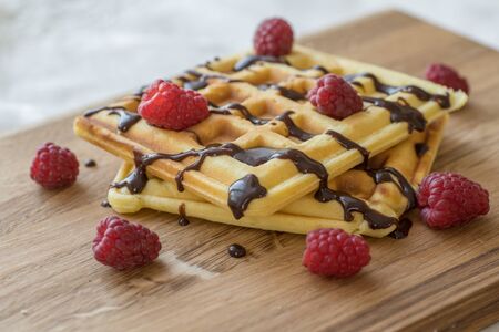 Viennese waffles with chocolate and berries on a wooden Boardの写真素材