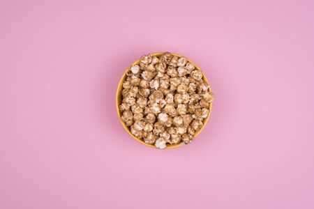 Caramel sweet popcorn bowl isolated on pink background top view. Frame composition with copy space.の写真素材