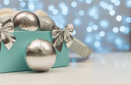 Blue box with silver Christmas balls on the background of blue bokeh lights on white background, New Year and Christmas decorationの写真素材