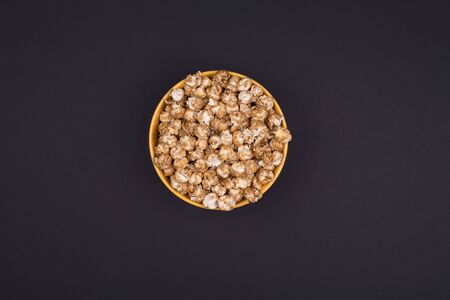 Caramel sweet popcorn bowl isolated on black background top view. Frame composition with copy space.の写真素材