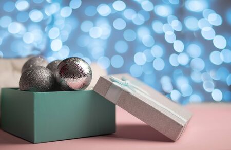 Blue box with silver Christmas balls on the background of blue bokeh lights on white backgroundの写真素材