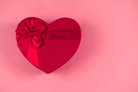 Red gift box heart shape with red ribbon on a pink background, gift concept, flat lay, mock upの写真素材