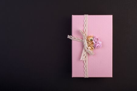 Rectangular pink gift box with bow and flowers on black background, gift on 8 march, top viewの写真素材