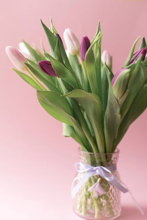 bouquet of pink and purple tulips in a vase on pink background, spring flowers for women, copy spaceの写真素材